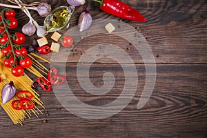 Ingredients for cooking spaghetti - raw pasta, tomato, olive oil, spices, herbs