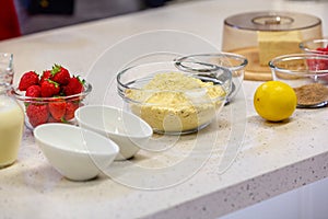 Ingredients for cooking strawberry pie or cake on white background. Side view. Flour, milk, sugar, strawberry, lemon