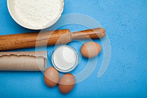 Ingredients and cooking utensils for making a cake or dessert on a blue table