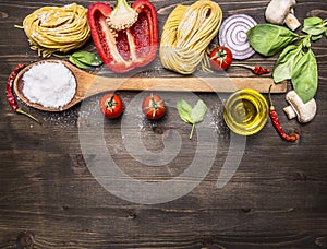 Ingredients for cooking vegetarian pasta with vegetables, a wooden spoon, herbs and butter on wooden rustic background top view cl