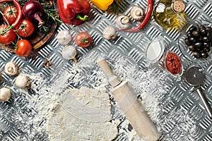 Ingredients and dough for making pizzas with an overhead view on freshly mixed mounds of pastry, a jar of olive oil and