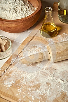 Ingredients for dough on pastry board with flour and rolling pin on table