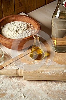 Ingredients for dough on pastry board with flour and rolling pin on table