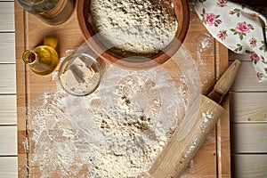 Ingredients for dough on pastry board with flour and rolling pin on table