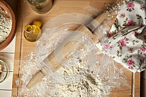 Ingredients for dough on pastry board with flour and rolling pin on table