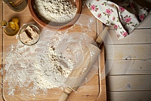 Ingredients for dough on pastry board with flour and rolling pin on table