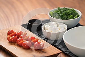 Ingredients and empty white bowl on walnut table