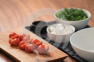 Ingredients and empty white bowl on walnut table