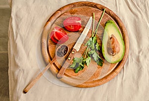 Ingredients for guacamole on a wooden board. Parsley, avocado, tomatoes, garlic, black pepper