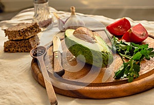 Ingredients for guacamole on a wooden board. Parsley, avocado, tomatoes, garlic, black pepper