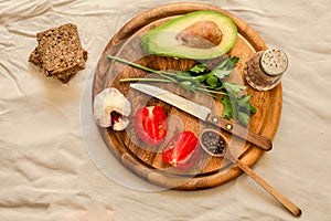 Ingredients for guacamole on a wooden board. Parsley, avocado, tomatoes, garlic, black pepper.Top view