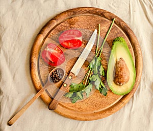 Ingredients for guacamole on a wooden board. Parsley, avocado, tomatoes, garlic, black pepper.Top view