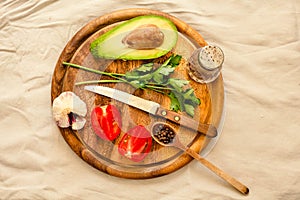 Ingredients for guacamole on a wooden board. Parsley, avocado, tomatoes, garlic, black pepper.Top view