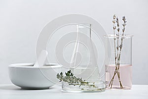 Ingredients for herbal cosmetic products and  laboratory glassware on white table