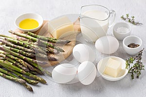 Ingredients for homemade asparagus omelet: fresh asparagus, eggs, milk or cream, butter, olive oil, cheese, salt, pepper, thyme on