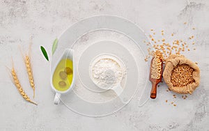 The ingredients for homemade pizza dough with wheat ears ,wheat flour and olive oil set up on white concrete background. top view