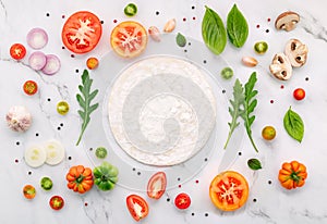 The ingredients for homemade pizza set up on white marble background