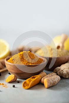 Ingredients for hot ayurvedic drink. Turmeric powder, curcuma root, cinnamon, ginger, lemon over grey background. Copy