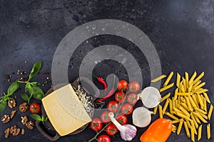 Ingredients for Italian dish. Parmesan cheese, pasta and fresh vegetables. On an old wooden background.