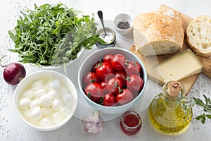 Ingredients for italian panzanella salad: cherry, arugula, basil, mozzarella, ciabatta bread, parmesan cheese, olive oil