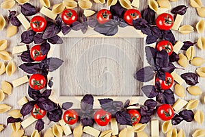 Ingredients Italian pasta - tomatoes, basil, cheese, macaroni on beige board with empty copy space as decorative frame background