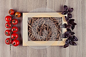 Ingredients Italian pasta in wood frame on beige wooden board as decorative picture background.