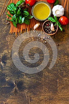 Ingredients for italy cuisine. Tomato spaghetti, herbs spices, olive oil and vegetables on a wooden table.