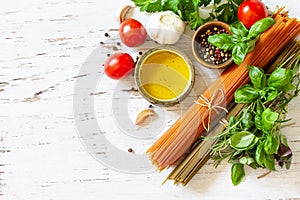 Ingredients for italy cuisine. Tomato and spinach spaghetti, herbs spices, olive oil and vegetables on a table.