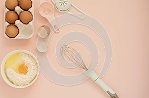 Ingredients and kitchen bake tools for cooking cake or sweets - eggs, flour, whisk on a pastel punchy pink background. Top view of