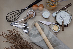Ingredients and kitchen items for baking cakes. flour, eggs, butter, milk and honey on light brown table. Baking background