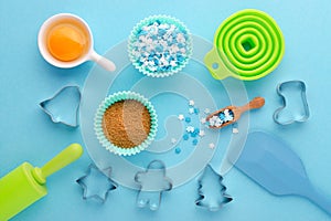 Ingredients and kitchen tools for baking with cookies cutter on blue background, flat lay