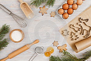 Ingredients and kitchen tools for cooking Christmas baking on light wood table top . Flour, eggs, rolling pin, cutters, sieve etc