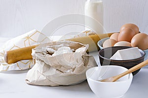 Ingredients for kneading the dough.Flour in the paper bag, eggs, dry yeast, milk.Kitchen utensils and components for dough