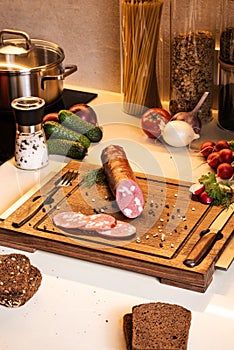 Ingredients for light snack. Smoked sausage on a wooden board with bread and fresh vegetables