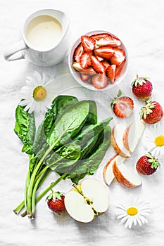Ingredients for making coconut probiotic yogurt, spinach, apple, strawberry detox smoothie on a light background, top view.