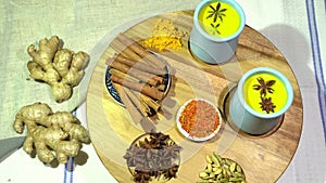 Ingredients for making Golden milk: turmeric, cinnamon, anise, star anise, ginger, and Golden milk in ceramic cups on a wooden tab