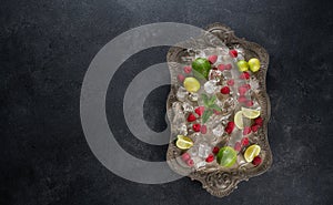 Ingredients for making lemonade Ice cubes, raspberry, lime, lemon and mint, served on old tray over dark rustic