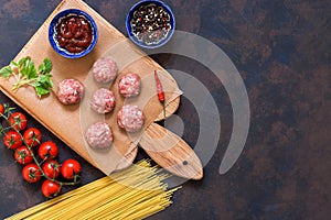 Ingredients for making meatballs with spaghetti on a blue-brown background. Raw meatballs on a cutting board. Top view, copy space