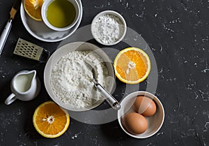 Ingredients for making orange cake with olive oil - flour, eggs, olive oil, powdered sugar on a dark background