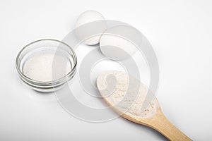 Ingredients for making pasta, pizza, cake, cookies. flour in a wooden spoon, sugar, eggs on a white background. products for cooki