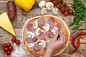 Ingredients for making pizza, before baking, on a wooden table, top view hand laid out mushrooms, step-by-step recipe