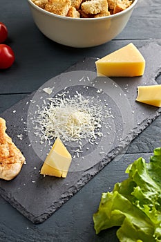 Ingredients for making salad. Piece and grated parmesan cheese on black serving board