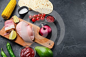 Ingredients for Mexican tacos with chicken meat, corn tortilla, salsa, chilli over black background, side view with space for text