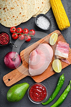 Ingredients for Mexican tacos with chicken meat, corn tortilla, salsa, chilli over black background, top view