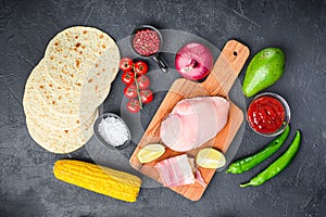 Ingredients for Mexican tacos with chicken meat, corn tortilla, salsa, chilli over black background, top view