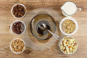 Ingredients for muesli in bowls, spoon in bowl, yogurt in jug on wooden table. Top view