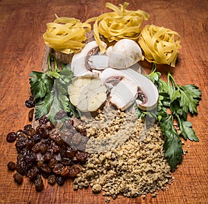 Ingredients nest pasta walnuts raisins herbs mushrooms on a cutting board wooden rustic background close up