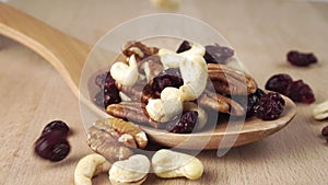 The ingredients of the nutty fruit mix fill the wooden spoon on the board.