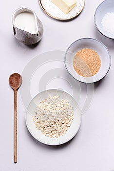 Ingredients for oat porridge: rolled oats or flakes, sugar, salt, milk and butter in a bowls