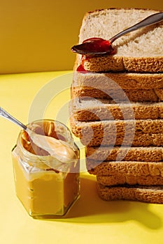 Ingredients for peanut butter and jelly sandwiches. Spoon with strawberry jam on pile of toast bread